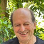 Homme souriant chauve en extérieur verdoyant