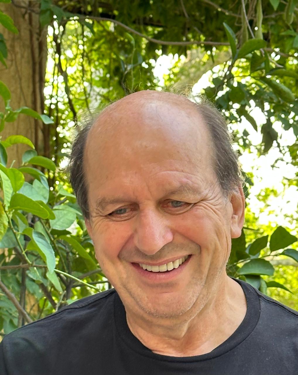 Homme souriant chauve en extérieur verdoyant